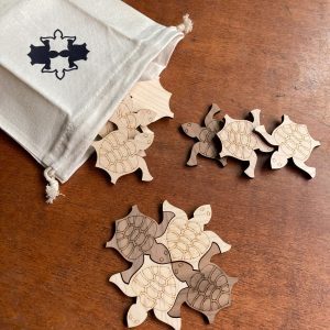 wooden tiling turtles spill out of a canvas bag that itself has an image of four tiled turtles on it