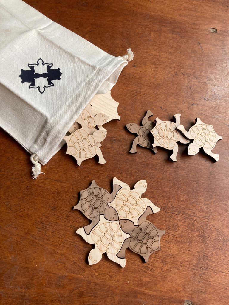 wooden tiling turtles spill out of a canvas bag that itself has an image of four tiled turtles on it