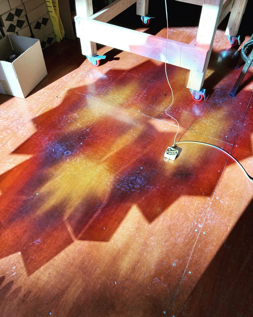 Sunlight streams through the large window, casting the colorful shadow the large pattern block arrangement on the floor.