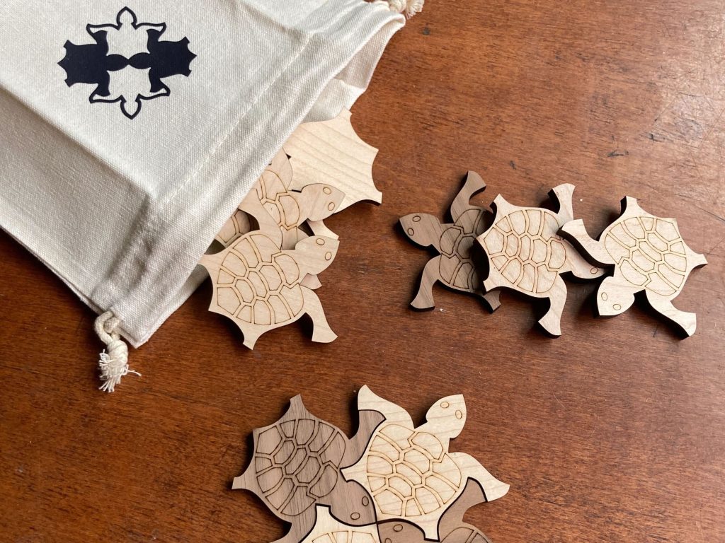 wooden tiling turtles spill out of a canvas bag that itself has an image of four tiled turtles on it