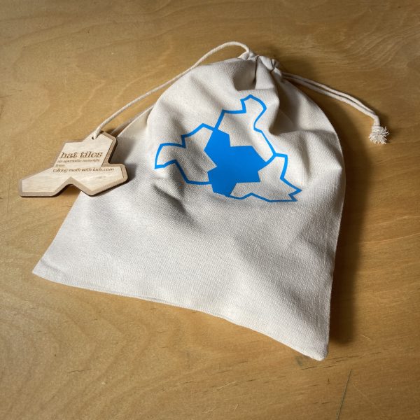 a canvas bag of hat tiles rests—lit by natural light—on a wooden table top.