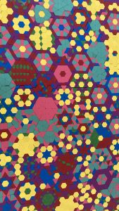 Overhead shot of part of the mosaic. There are many hexagons tiled together; maybe 75 or so partially or fully in view. Each is composed of many smaller, brightly colored shapes revealing a joyful diversity of geometric ideas.
