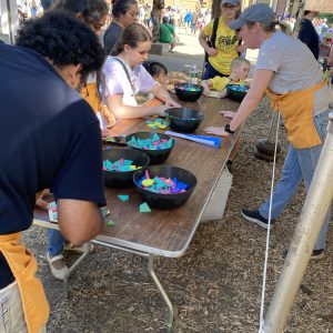 Several people at a wooden table outside, assembling hexagons from pattern blocks.