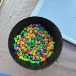 A plastic bowl with a mix of four or five colors; purple, light-green, and orange dominating.